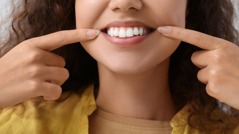 Close-up Of A Person Smiling And Pointing At Their Teeth